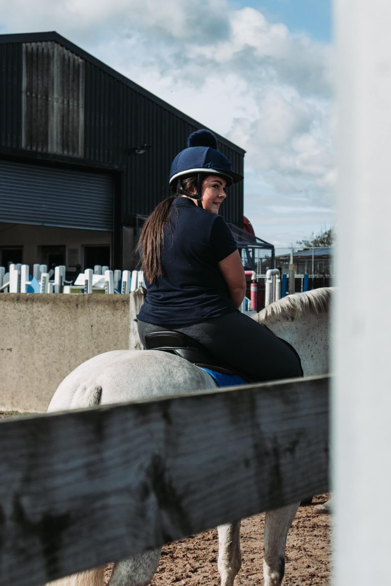 Lady riding a horse in a helmet at a school